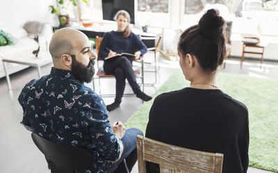 male and female sitting across from a therapist in her office