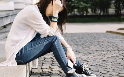 Depressed girl sitting at the street