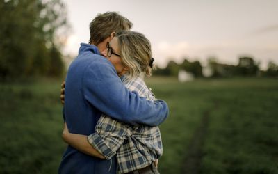 Couple hugging in a field at dusk