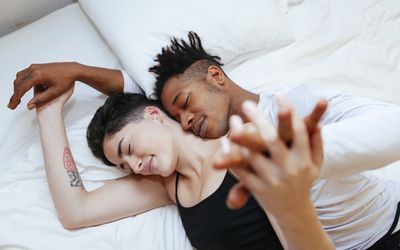 High Angle View Of Couple Lying On Bed At Home