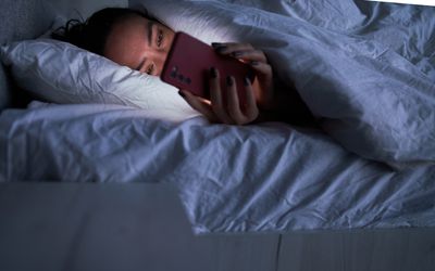 Lady messaging on smartphone in bed