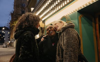 three women smiling outside a movie theater