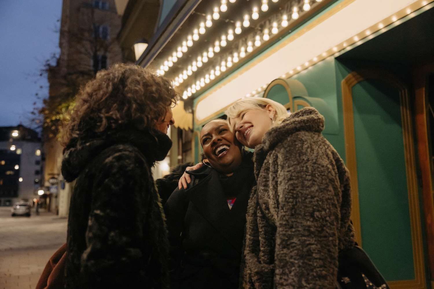 three women smiling outside a movie theater