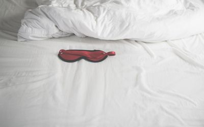 red mask on a bed with white sheets