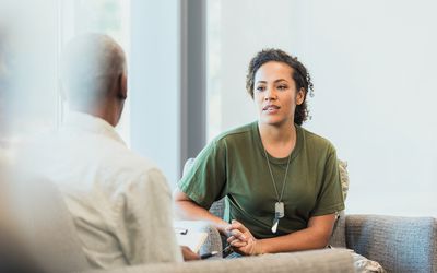 A serious mid adult female soldier talks to a male mental health professional about hard situations while serving overseas.