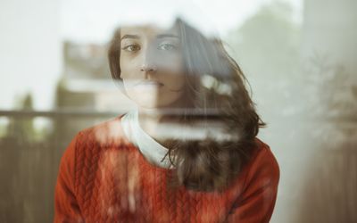 Portrait of serious young woman behind glass pane