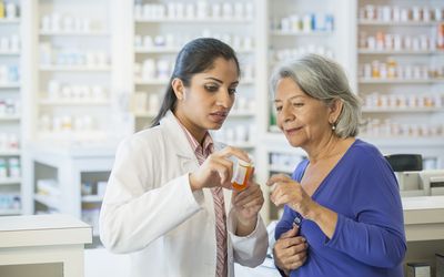 pharmacist holding a prescription bottle while explaining Zoloft side effects to a patient