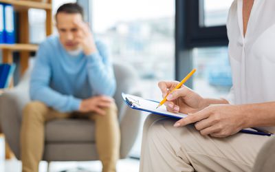 Psychologist taking notes with a patient in the background