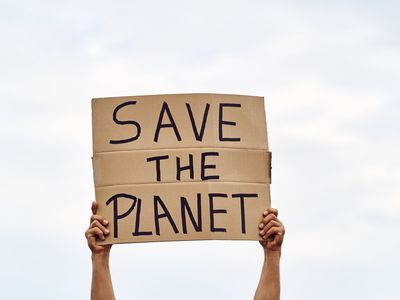 Unrecognizable man's hands holding a protest banner with the message SAVE THE PLANET, with the sky in the background. Concept of demonstration and activism climate change.