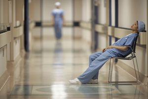 young doctor sitting in hallway looking stressed and tired