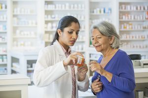 pharmacist holding a prescription bottle while explaining Zoloft side effects to a patient