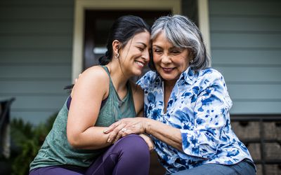 Senior woman and adult daughter laughing on porch