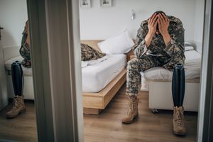 veteran sitting on the edge of the bed with his head in his hands