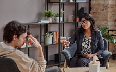 a person speaking to their therapist, while their therapist hands them a glass of water