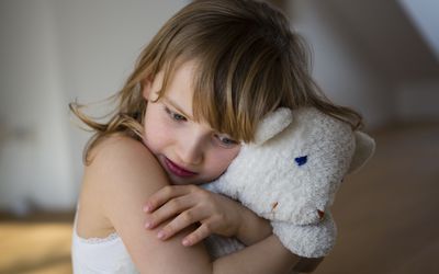 Sad girl hugging a stuffed animal