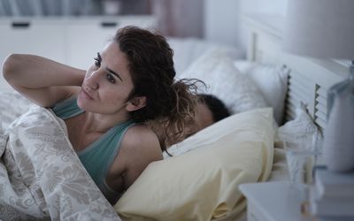 Anxious woman rubbing her neck in bed