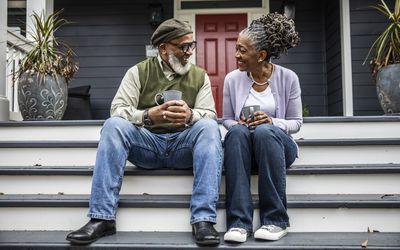 Senior couple having coffee in front of suburban home