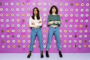Two young women posing at an indoor theme park with donuts at the wall