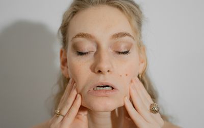 Woman doing face yoga exercises for health benefits. She is stretching her cheeks.