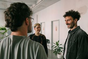 A male hispanic psychotherapist smiling with his two clients working in a pair. They are about to do an exercise of opening up to the other by means of eye gazing.