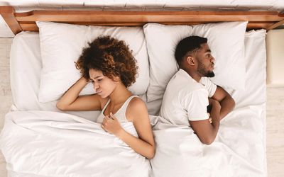 African-american couple ignoring each other in bed