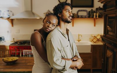 Young woman hugging her boyfriend while bonding with him at home 