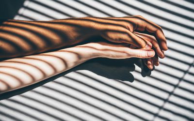 Interracial couple holding hands on the bed.