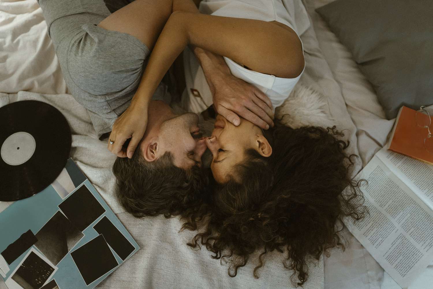 young couple lying on the led holding each other with a vinyl record next to them