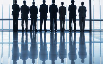 Silhouette of business people in a row looking out lobby window