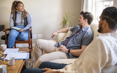 young woman talking to two men on a couch