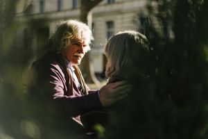 Gray haired senior man with hand resting on wife's shoulder in tender moment