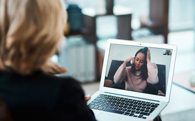 Shot of a young woman having a counselling session with a psychologist using a video conferencing tool