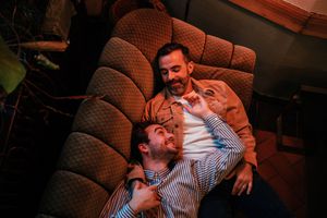 Two men snuggling on the couch, smiling at each other