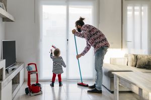 Father and little daughter cleaning the living room together