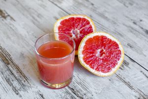 Sliced grapefruit and glass of grapefruit juice on wood