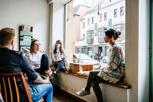 A group of friends are sitting down, relaxing and chatting with each other in a cafe.