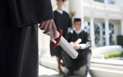 student standing with their psychology degree in their hand