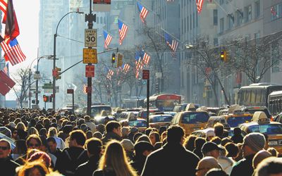 Crowd of people walking down a city sidewalk