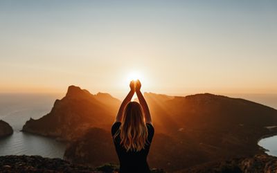 Woman with arms up at sunset.