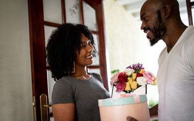 Husband surprising his wife with a flowers and present at home