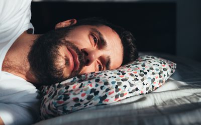 Young depressed man crying in bed