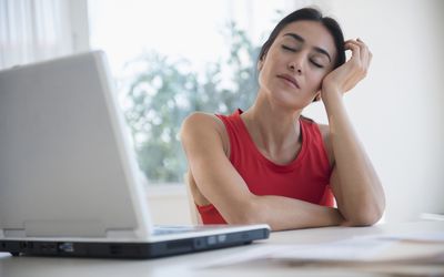 woman with eyes closed in front of laptop