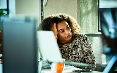 Portrait of mixed race woman looking bored at desk