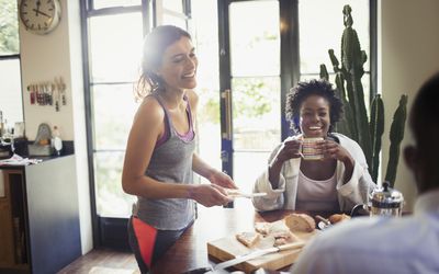 two smiling women enjoying breakfast at kitchen table