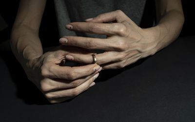 A woman divorcing and taking off her wedding ring in a moody background