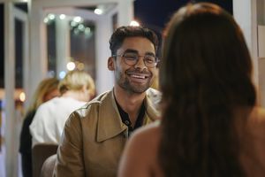 Young man talking and laughing with a young woman while sitting at a restaurant table during a dinner date