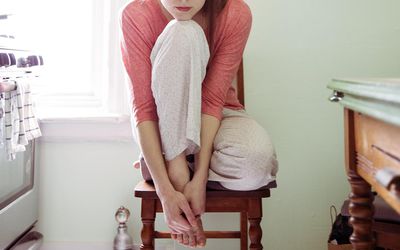 Young Woman Sitting In Kitchen Alone