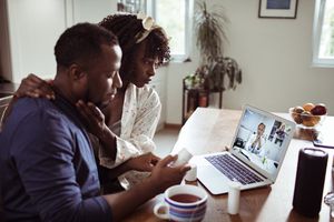 Close up of a young African couple consulting with their doctor over a video call on the laptop