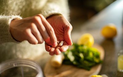 Close up of a Young woman taking a health supplement in the kitchen