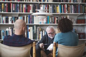 Senior therapist explaining analysis to mature couple against bookshelf at home